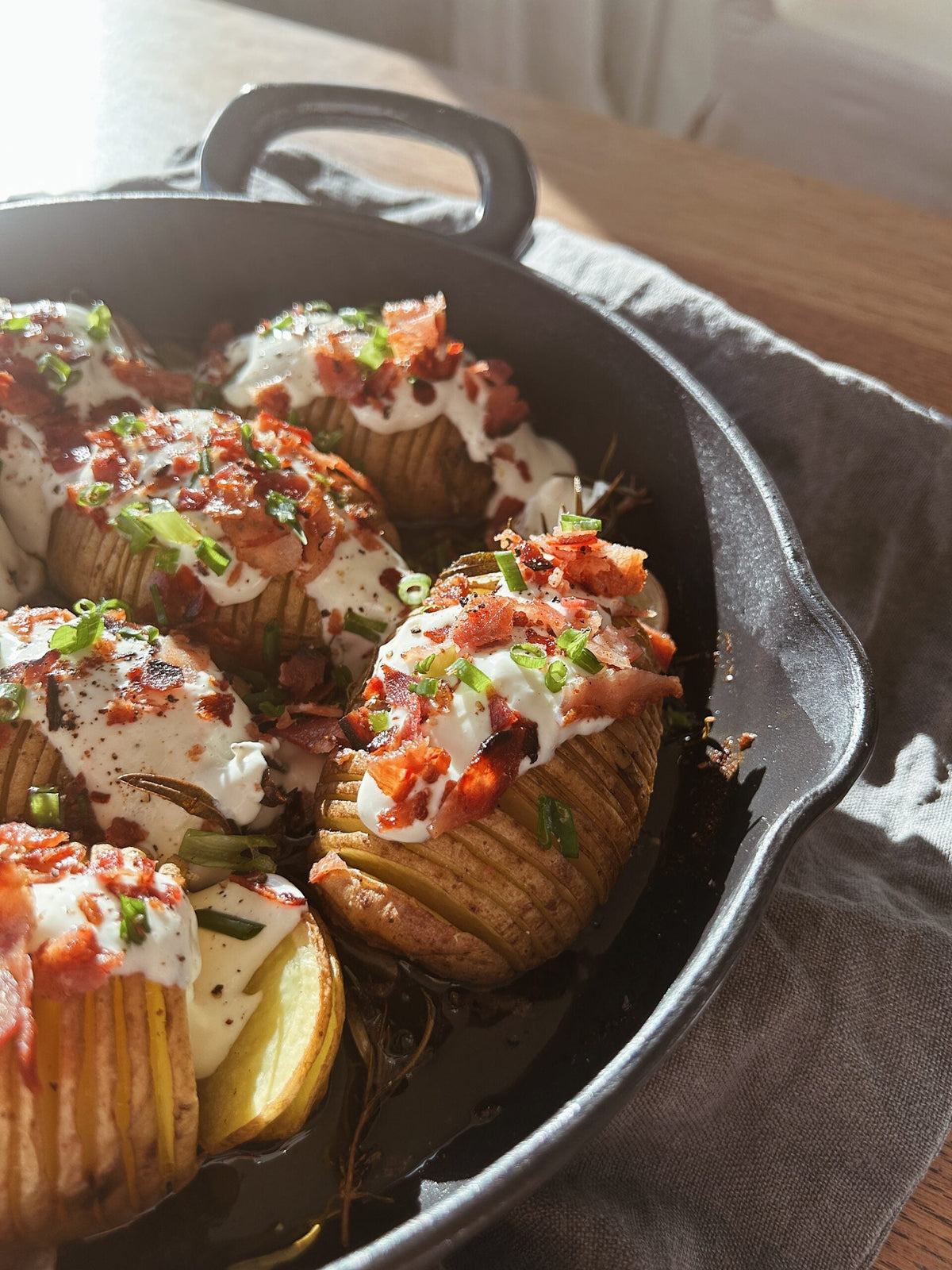 Hasselback-perunat valkosipulikastikkeen, pekonin ja kevätsipulin kera