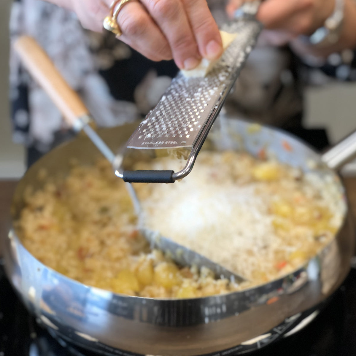 Teräksisellä viilaraastimella hienolla karkeudella raastetaan parmesaania pastan joukkoon.